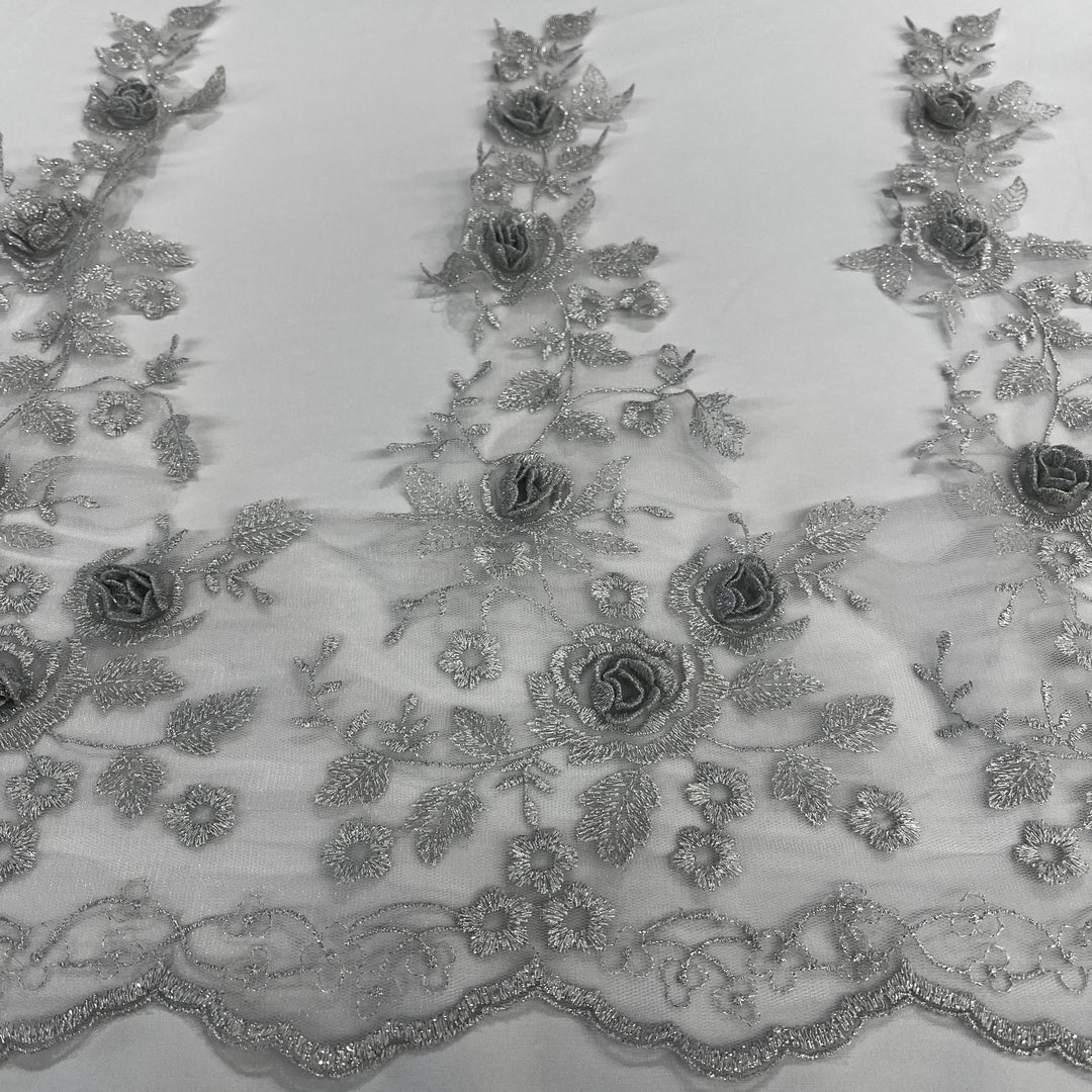 Silver floral embroidered lace trim featuring 3D rose appliqués, metallic thread embroidery, and a scalloped edge on soft tulle mesh., on a white background