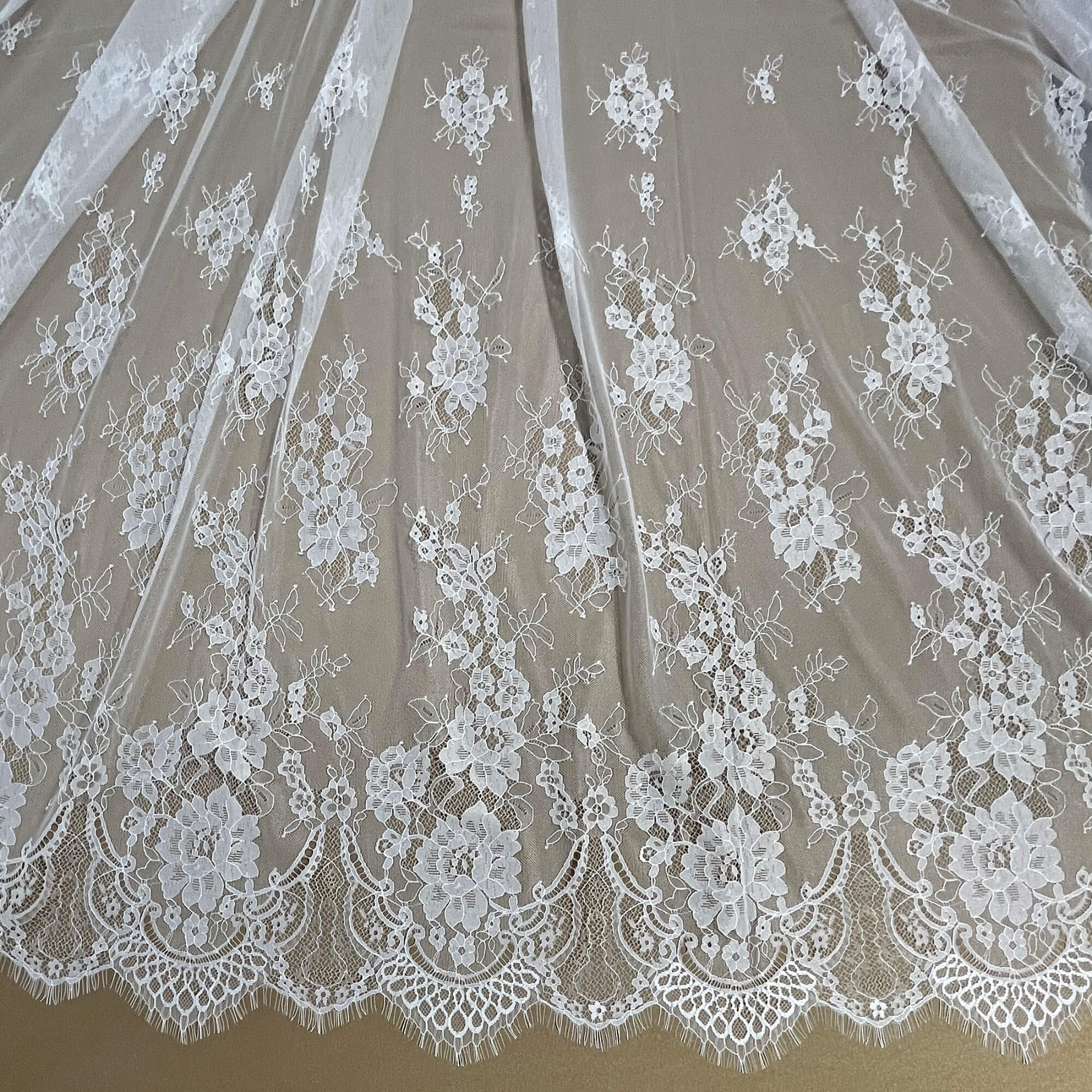 Close-up of Ivory/Off White  lace fabric with floral patterns on a brown background - LaceUSA-GDF-11