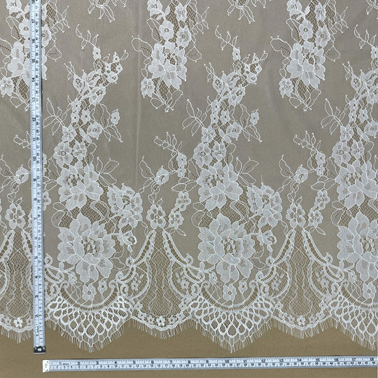 close-up of Ivory/Off white Chantilly lace fabric with floral design and scalloped eyelash edge, with measuring tapes for scale- LaceUSA-GDF-11