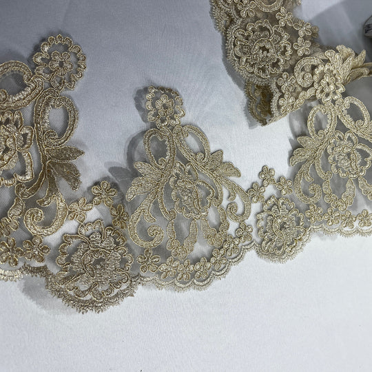 close up of Elegant gold floral embroidered lace trim featuring delicate cording and ornate paisley details