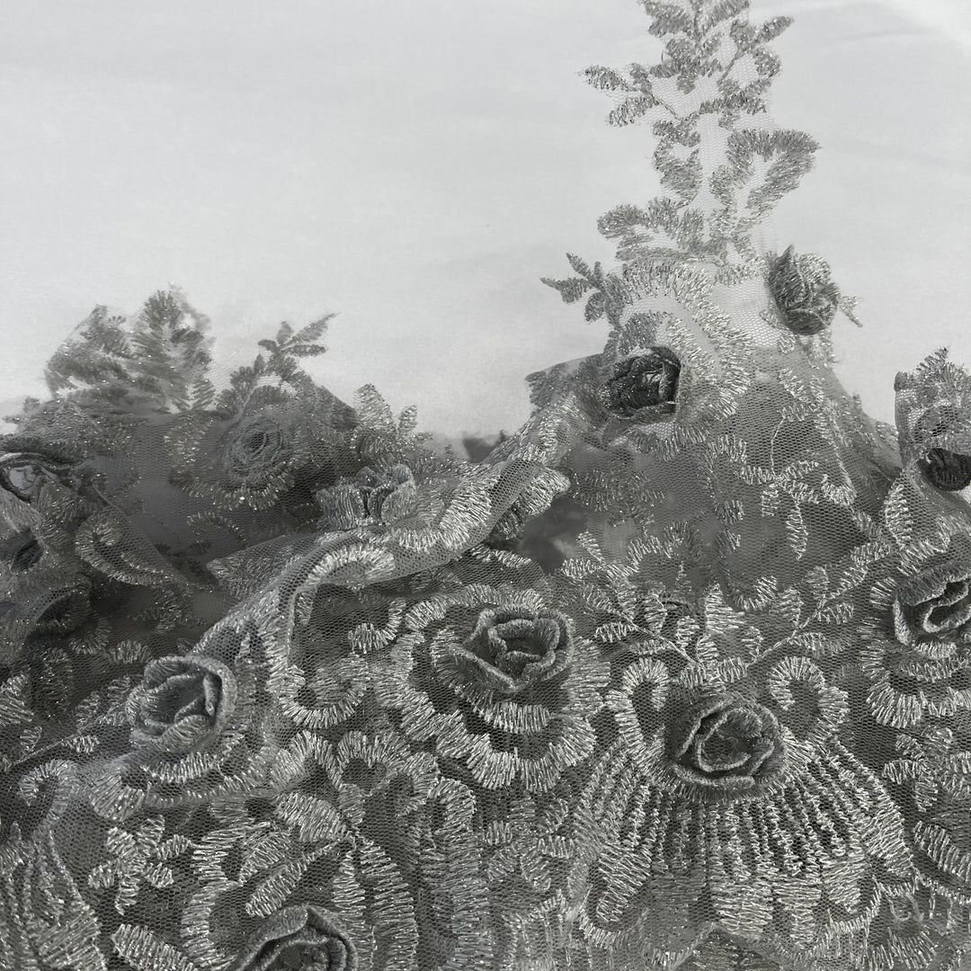 Close-up of a  floral lace trim with embroidered  3D rose motifs and delicate mesh texture in a silver color. Lace USA #21856W