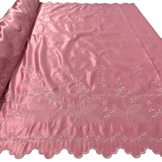 Dusty Rose satin fabric with delicate floral embroidery and a scalloped edge, shown partially rolled on the left against a white background.