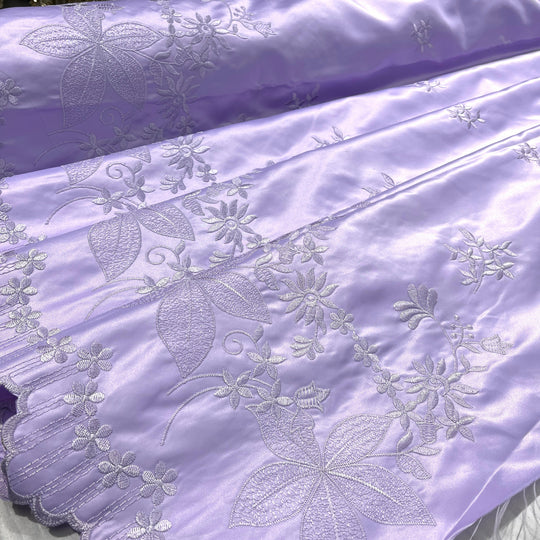 Lilac satin fabric with floral and leaf embroidery, featuring a scalloped edge.