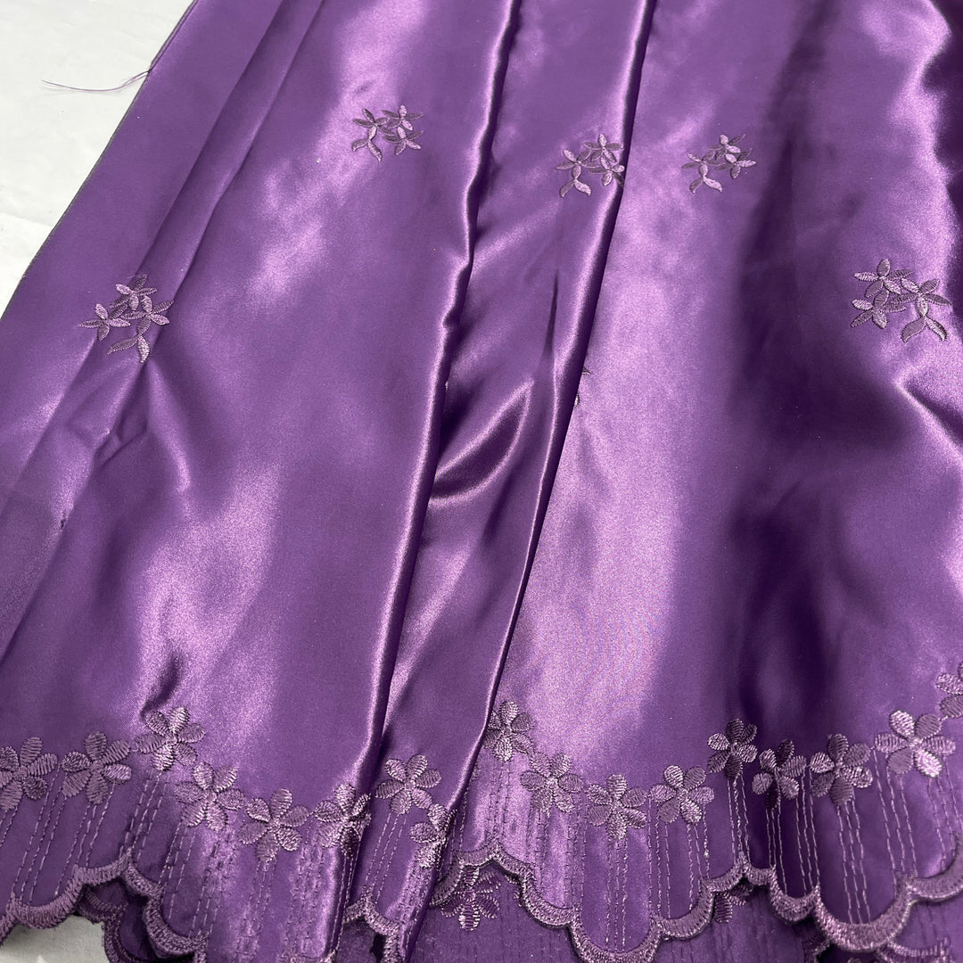 Plum satin fabric with embroidered floral motifs and a scalloped hem, shown in a close-up product shot.