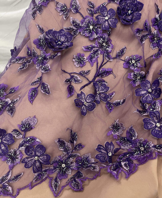 Close-up of Lace USA GD-1613 3D purple floral lace with bead and rhinestone embellishments, displayed over champagne fabric—ideal for gowns.